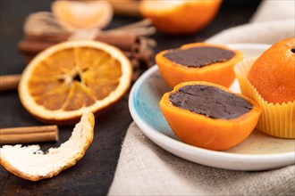 Truffle chocolate tangerine candies on a black concrete background and linen textile. Side view,