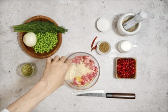 Top view of male hand pouring breadcrumbs into a bowl of minced meat. Process of preparing minced