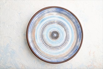 Empty blue ceramic plate on white concrete background. Top view, close up, flat lay