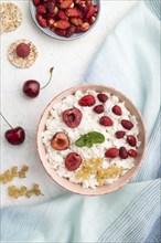 Rice flakes porridge with milk and strawberry in ceramic bowl on white concrete background and blue