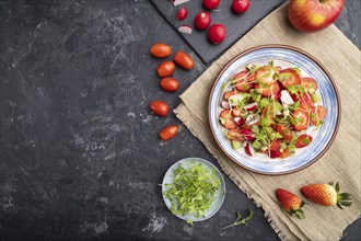 Vegetarian fruits and vegetables salad of strawberry, kiwi, tomatoes, microgreen sprouts on black