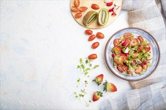 Vegetarian fruits and vegetables salad of strawberry, kiwi, tomatoes, microgreen sprouts on white