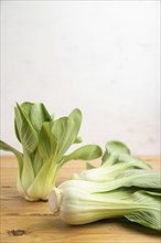 Fresh green bok choy or pac choi chinese cabbage on a brown wooden background. Side view, copy