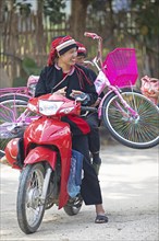 Vietnamese woman in traditional traditional costume from the Dao minority transport a pink bicycle