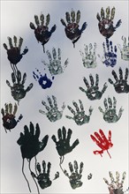 Handprints on a white wall, single red print between many grey ones, Duisburg, North