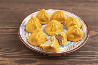 Fried manti dumplings on brown wooden background. Side view, close up