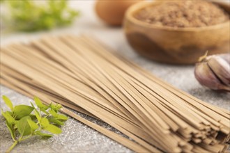 Japanese buckwheat soba noodles with tomato, eggs, spices, herbs on brown concrete background. Side