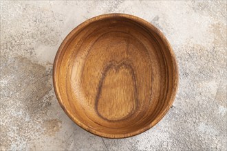 Empty brown wooden bowl on brown concrete background. Top view, copy space, flat lay