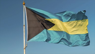 The flag of the Bahamas flutters in the wind, isolated against a blue sky