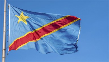 The flag of the Democratic Republic of the Congo flutters in the wind, isolated against a blue sky