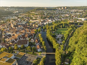 Wide aerial view of a town with a river, bridge and many houses surrounded by green hills, Nagold,