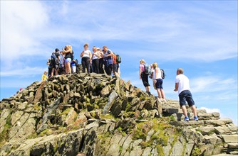 Walkers crowd onto the summit point, Mount Snowdon, Gwynedd, Snowdonia, north Wales, UK