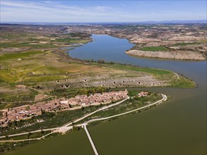 A wide aerial view shows a winding river landscape with a village and green hills, aerial view,