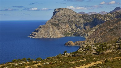 Rocky coastal landscape above a deep blue sea under a clear sky, Mesochori village, west coast,