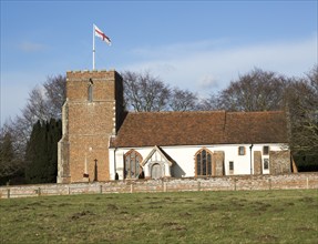 Red cross of flag of St George flying from tower of village Saint Peter church, Levington, Suffolk,