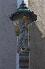 Sculpture of St Mary with the infant Jesus under a canopy on the corner of a house, Regensburg,