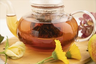 Red tea with herbs in glass teapot on white wooden background. Healthy drink concept. Top view,