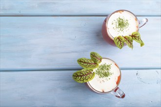 Tomato juice with sorrel and sour cream in glass on blue wooden background. Healthy drink concept.