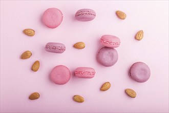 Purple and pink macaron or macaroon cakes with almonds on pastel pink background. Morninig, spring,