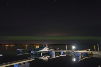 Northern lights (aurora borealis) shine on a starry night over Lake Plau, Ganzlin,