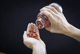 A person pours tablets from a can into his hand in Berlin, 09/08/2024