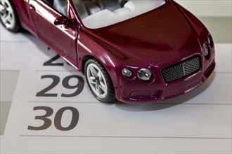 Deadline for changing car insurance (symbolic image with model car and calendar)