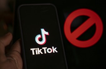 In this photo illustration, logo of Tiktok is displayed on mobile phone screen next to ban sign, in