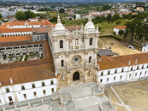 The picture shows a historic monastery with baroque architecture in an urban landscape, aerial