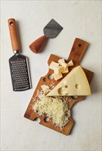 Grated cheese, Maasdam, on a cutting board, grater and cheese knife, close-up, no people