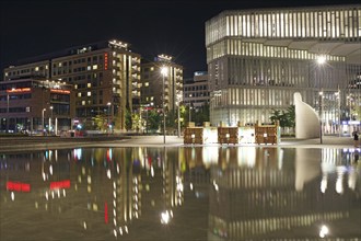 Night shot of a modern city with illuminated buildings reflected in the water, public library,