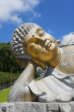 Close-up of a reclining Buddha statue radiating meditative calm against a clear blue sky, Bacalhôa,