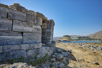 Ruin of an old stone tower with a view of the rocky coast and the blue water in the distance, tomb