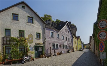 Bright, cobbled alleyway Vils Gasse with colourful buildings and rock face in the background,