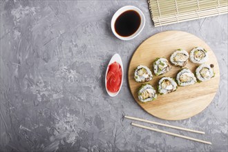 Japanese maki sushi rolls with green onion, chopsticks, soy sauce and marinated ginger on wooden