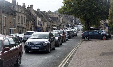 Tourist honeypot village street crowded with traffic in Burford, Oxfordshire, England, UK