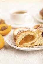 Homemade sweet bun with apricot jam and cup of coffee on gray concrete background. side view, close