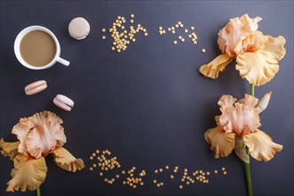 Orange iris flowers and a cup of coffee on a black background. Morninig, spring, fashion