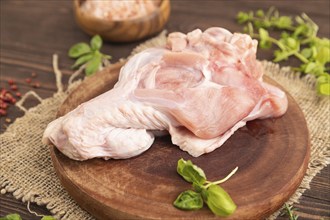 Raw turkey wing with herbs and spices on a wooden cutting board on a brown wooden background and