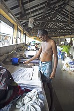 Indian man ironing laundry at Dhoby Khana laundry, Kochi, Kerala, India, Asia