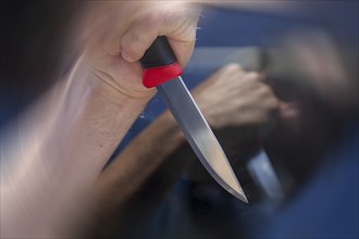 Symbolic image of a knife attack: close-up of a knife in a man's hand