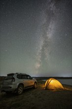 Off-road vehicle and tent, night shot, Milky Way at Lake Issyk Kul, Kyrgyzstan, Asia