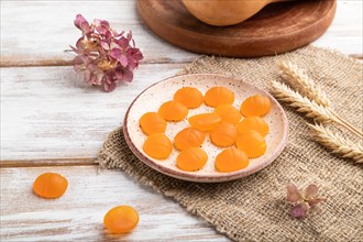 Jelly pumpkin candies on white wooden background and linen textile. close up, side view. autumn