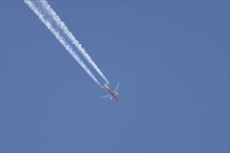 Boeing 767 jet cargo aircraft of DHL flying in a blue sky with a vapor trail or contrail behind,