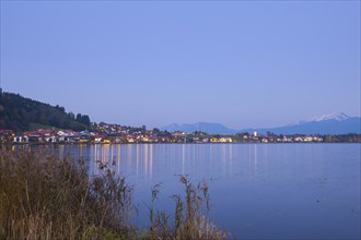 Village on the lakeshore at dusk, mountains in the background, quiet atmosphere, Hopfen am See,