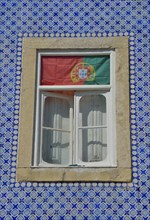 House facade with azulejos wall tiles and the Portuguese flag in the window, historic city