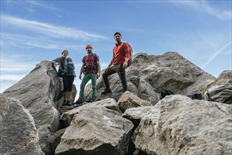 A group of climbing friends, smiling and looking at the camera at the top of the rock. Mixed rock