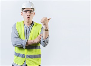 Portrait of surprised engineer man pointing side. Amazed engineer pointing advertising to side