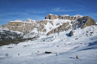 View of a ski resort piste with people skiing in Dolomites in Italy. Ski area Belvedere. Canazei,