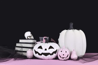 Pink and white Halloween decor with black and white pumpkins, spell books and spiders on black