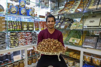 Seller with a bowl of dates, Date market, Abu Dhabi City, Emirate of Abu Dhabi, United Arab